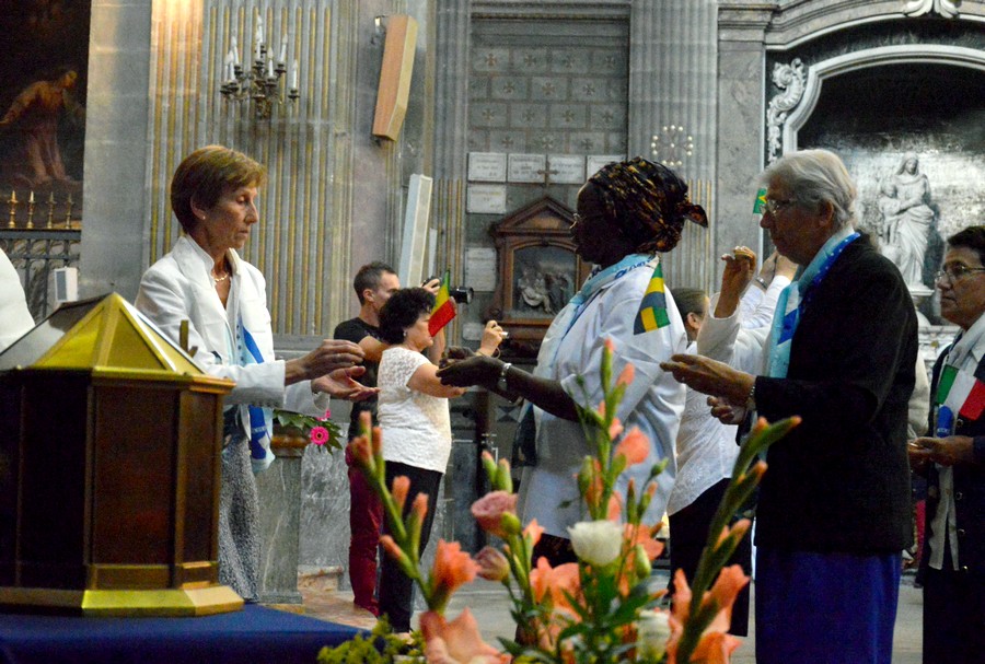 Des sœurs apportent près du reliquaire et du tableau d’Emilie des drapeaux de tous les pays où la congrégation est présente